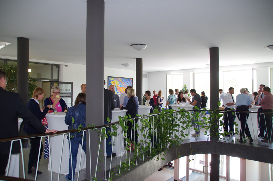 Zu sehen ist das mit Stehtischen ausgestattete Foyer vor dem Hörsaal. In den Veranstaltungspausen konnten die Teilnehmer sich dort stärken und miteinander ins Gespräch kommen. 