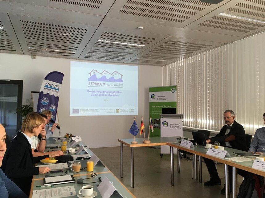 Sitzungsraum mit Teilnehmern des 3. Projektkoordinationstreffens im Leibniz-Institut für ökologische Raumentwicklung in Dresden. Im Hintergrund ist die Startfolie einer Power-Point Präsentation an der Wand zu sehen.